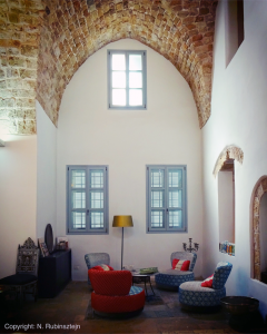 Picture of Hotel Efendi in Akko built in Ottoman style, with blue sofa's, red pillows and three windows