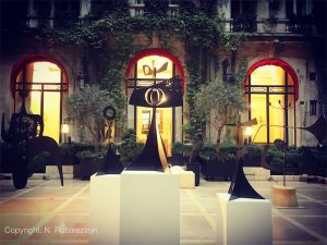 Picture of La Cour Jardin at Hotel Plaza Athénée in Paris. The picture features modern sculptures exhibited in the hotel. The 5 sculptures are surrounded by the hotel lobby.