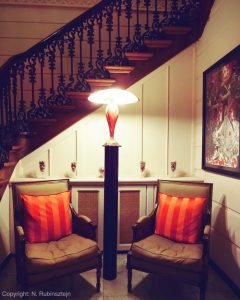 Picture of Hotel 't Sandt in Antwerp. Two chairs and an Art Deco lamp, surrounded by a wooden and classic staircase.