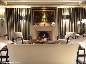 Picture of Hôtel Esprit Saint-Germain in Paris, featuring its lobby which looks like a living room. It is composed of floor lamps, beige sofas, a modern art painting, shining curtains and a fireplace.