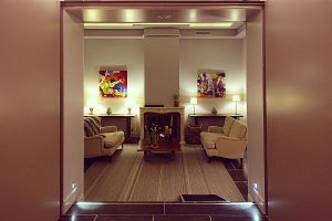 Picture of Le Dixseptième in Brussels featuring one of the hotel's lobbies. The sofas are beige and are covered by covers, surrounded by colorful modern paintings and a fireplace.