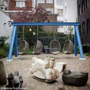 Photo of the Pulitzer Amsterdam featuring its garden which contains a swing and a wooden swinging horse.