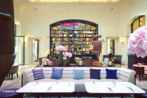 Hotel Lutetia in Paris, featuring its lobby with its grand bookcase, sofas, modern sculptures and pink flowers.